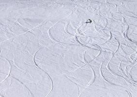 Snowboarder bergab auf Pistenhang mit Neuschnee