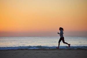 Fitnessfrau läuft am Strand