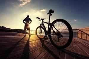 Schattenbild des Sportlers und des Mountainbikes bei Sonnenuntergang foto