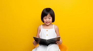 asiatische Mädchen sitzen und lesen ein Buch und lächeln glücklich. Selbstlesekonzept in der Kindheit. kluges Kind. kreatives kind. kluges Kind. foto