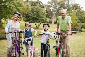 glückliche Großeltern mit ihren Enkelkindern auf Fahrrädern foto
