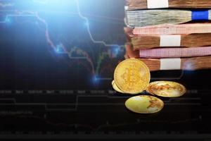 kryptowährungssymbol mit kopierraum. Die glänzende Bitcoin-Goldmünze hebt sich von anderen Münzen und vielen Banknoten mit Forex-Wachstumsdiagramm ab. foto