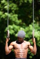 Afroamerikanermann-Trainingsroutine auf Turnerringen foto