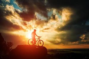 Schattenbild eines Bikers und des Fahrrads auf Himmelhintergrund. foto