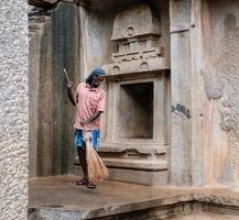 mamallapuram, tamil nadu, indien - august 2018 eine alte indische kehrmaschine reinigt den boden der alten pallava-höhlen in mahabalipuram mit einem holzbesen. foto