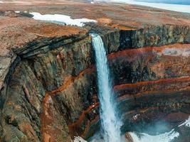 Luftaufnahme des Hengifoss-Wasserfalls mit Sedimenten mit roten Streifen in Island. foto
