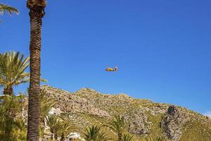 Wasserflugzeug canadair fliegt über felsige Klippen gegen den klaren blauen Himmel foto