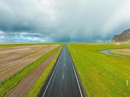 endlose straße in die bewölkten berge und hügel von island bei sonnigem bewölktem wetter. foto