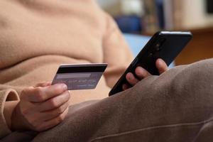 nahaufnahme hand mit kreditkarte bezahlen kontaktlos online beim mobilen app-shopping foto