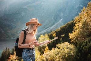 fernweh und reisekonzept. stilvolles reisendes mädchen mit hut, das karte betrachtet und wälder erkundet. foto