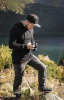 Fotograf des jungen Mannes, der Fotos mit Digitalkamera in den Bergen macht.