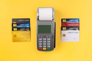 Stapel von Kreditkarten und Kartenlesegerät mit Rechnung auf gelbem Hintergrund. Online-Zahlungskonzept. foto