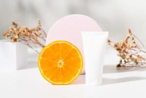 Flaschenröhrchen mit Orangenscheibe, Inhaltsstoffe für Hautpflege und Behandlungsvitamin auf weißem Hintergrund, Naturkosmetikkonzept. foto