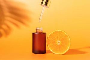 Serumflasche mit Tropfer und Orangenscheibe, Inhaltsstoffe für Hautpflege und Behandlungsvitamin auf weißem Hintergrund, Naturkosmetikkonzept. foto