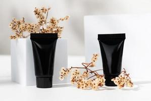 Schwarzes Flaschenrohr mit Inhaltsstoffen für Hautpflege- und Behandlungsvitamin auf weißem Hintergrund, Naturkosmetikkonzept. foto