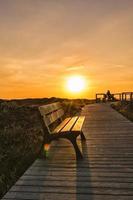 einsame Bank auf Seeküste Fußweg und Schönheit Sonnenuntergang vertikal
