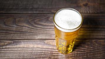 kaltes handwerkliches leichtes bier gießt aus der flasche auf den holztisch foto