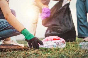 frauenhand, die müllplastikflasche zur reinigung im park aufhebt foto