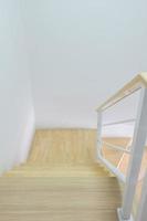 Moderne geschwungene Holztreppe mit dem weißen Metallhandlauf im Stadthaus. foto