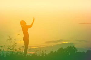 Silhouette einer Frau, die über einem schönen Himmelshintergrund betet foto