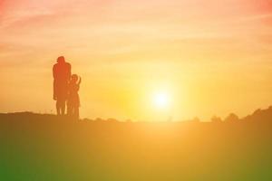 Mutter ermutigte ihre Tochter bei Sonnenuntergang aus dem Schatten. foto