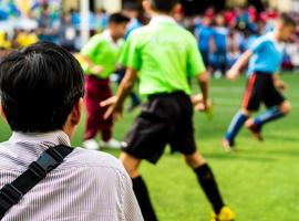 Mann in Arbeitsuniform sieht sich die Fußballwettbewerbe neben dem Fußballplatz an foto