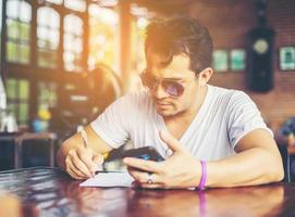 junger Mann mit lächelndem Smartphone, der sich im Café entspannt. foto