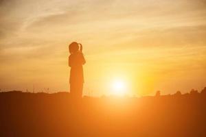 Kindersilhouette, Momente der Freude des Kindes. auf dem natursonnenuntergang foto