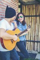 junger Hipster-Mann, der Gitarre spielt, um sich in seinem Urlaub zu entspannen, mit natürlicher und frischer Luft zu genießen. foto