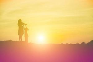 Mutter ermutigte ihre Tochter bei Sonnenuntergang aus dem Schatten. foto