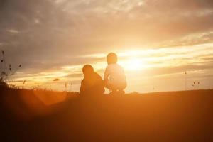 silhouette eines glücklichen kinder- und glücklichen zeitsonnenuntergangs foto