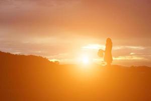 Silhouette einer Frau, die über einem schönen Himmelshintergrund betet foto