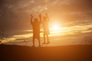 silhouette eines glücklichen kinder- und glücklichen zeitsonnenuntergangs foto