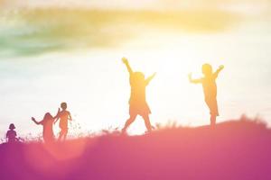 silhouette eines glücklichen kinder- und glücklichen zeitsonnenuntergangs foto