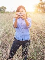 jahrgang der schönen frauenfotografie stehende hand, die retro-kamera mit sonnenaufgang hält, weicher traumstil foto