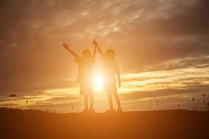 silhouette eines glücklichen kinder- und glücklichen zeitsonnenuntergangs foto