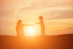 mutter ermutigte ihren sohn im freien bei sonnenuntergang, silhouettenkonzept foto