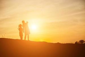 Mutter ermutigte ihre Tochter bei Sonnenuntergang aus dem Schatten. foto