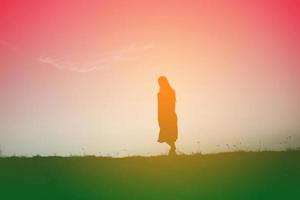 Silhouette einer jungen Frau, die allein steht foto
