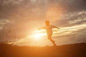 Kindersilhouette, Momente der Freude des Kindes. auf dem natursonnenuntergang foto