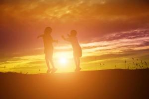 silhouette eines glücklichen kinder- und glücklichen zeitsonnenuntergangs foto