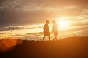 silhouette eines glücklichen kinder- und glücklichen zeitsonnenuntergangs foto