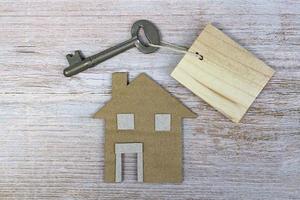 Hausmodell und Schlüssel auf Holzschreibtisch. direkt darüber. flach liegen. foto
