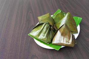 malaysische Delikatessen Kuih Koci im Bananenblatt auf Holzschreibtisch. foto