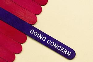 Going Concern-Text auf violettem Holzstab. Buchhaltungskonzept. foto