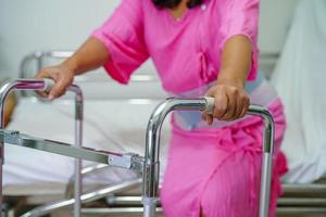 asiatische Dame mittleren Alters Patientin geht mit Walker auf der Krankenstation spazieren foto