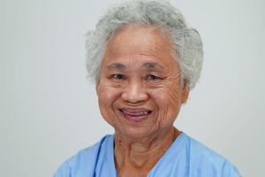 asiatische ältere seniorin, patientin, sitzend und lächelndes gesicht mit glücklichem auf dem bett im krankenhaus. foto