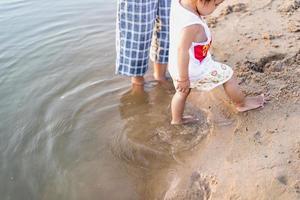 Eine junge Mutter spielt im Sommer mit ihrer 2-5 Jahre alten Tochter am Strand. Outdoor-Resort am See erholen Sie sich an Wochenenden, Familientagen. foto