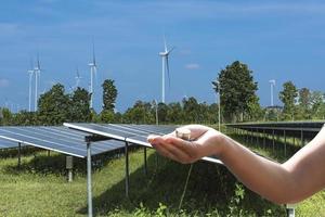 Erneuerbare Energien Ökonomie Geld in der Handfläche vor Sonnenkollektoren und Windkraftanlagen. dreidimensionale Illustrationen. foto