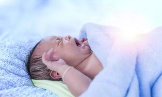 neugeborenes baby weint neugeboren müde und hungrig im bett unter blauer strickdecke. Baby weint Babybettwäsche, Baby schreit. foto